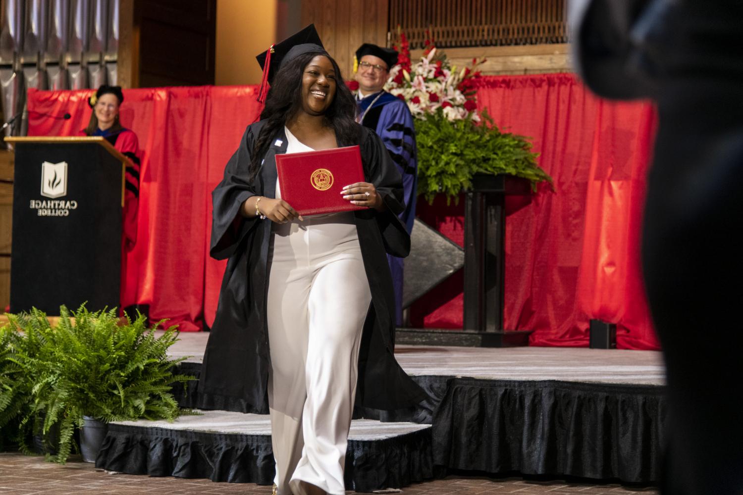 A 2023 <a href='http://l7cm.vijethaschool.com'>BETVLCTOR伟德登录</a> graduate beams as she leaves the Commencement stage after receiving her diploma from Carthage President John 吞下.